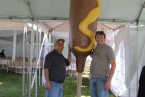 Two men with Giant Corn Dog prop